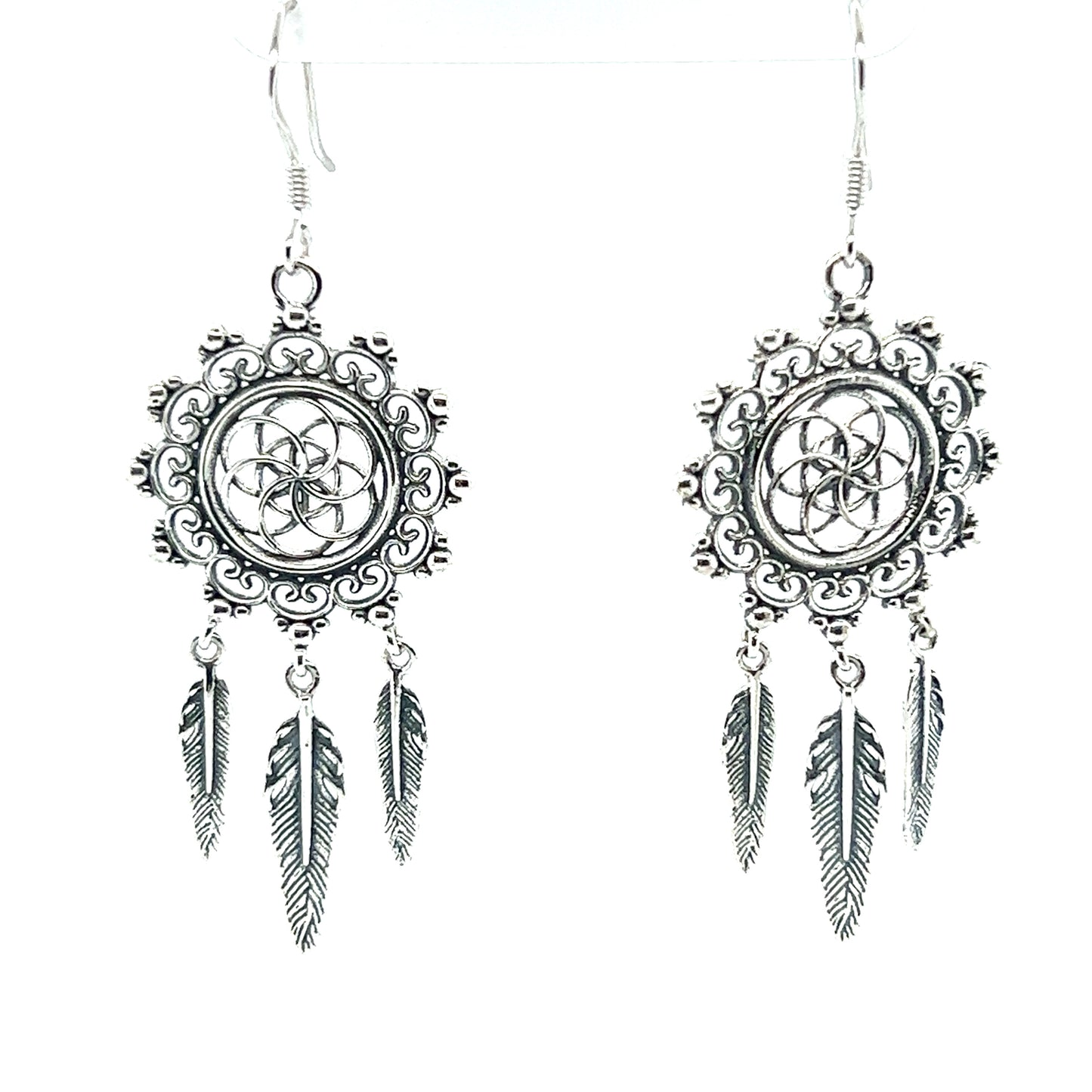 A pair of Super Silver Dreamcatcher Earrings With The Flower Of Life Symbol crafted in silver with delicately adorned feathers.