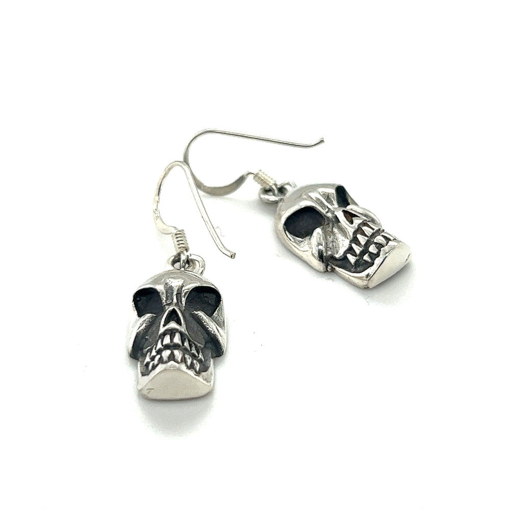 A pair of Super Silver skull earrings on a white background.