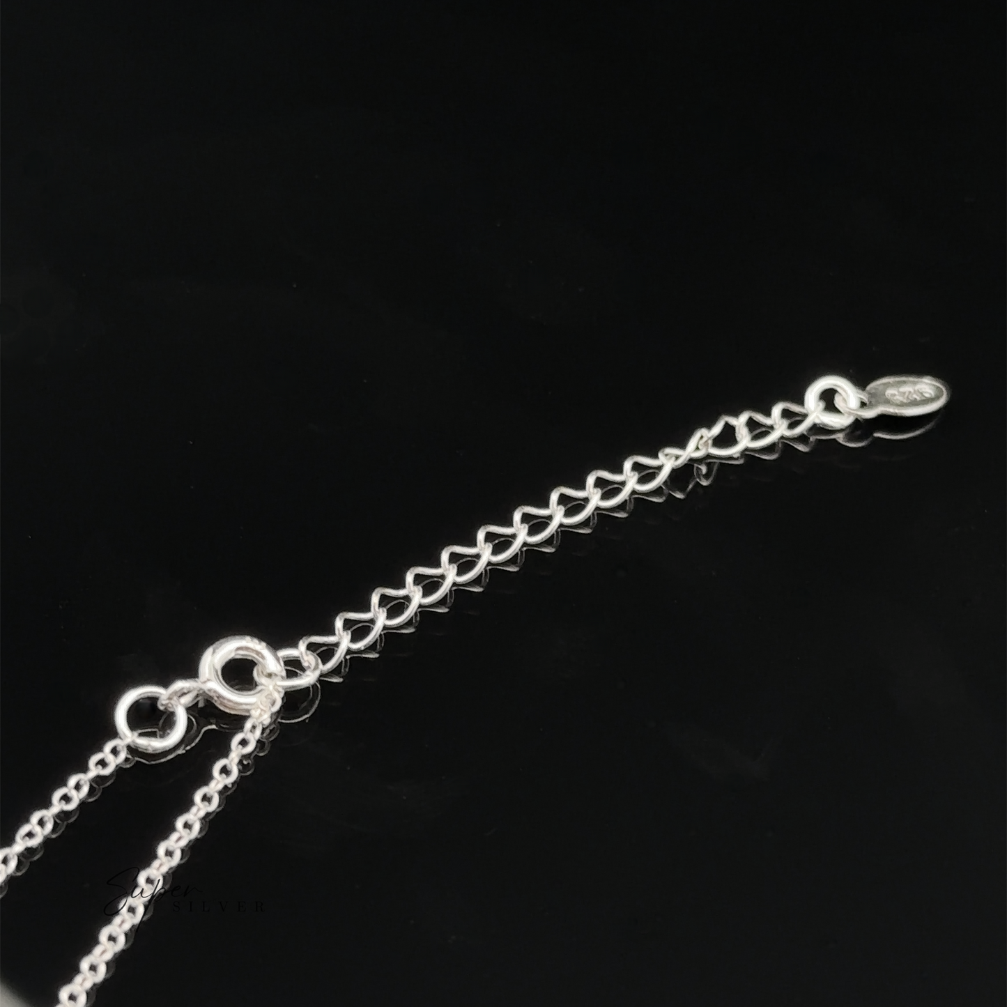 
                  
                    A close-up of the Silver Open Heart Charm Necklace, adorned with delicate open heart charms and an adjustable clasp, set against a black background.
                  
                
