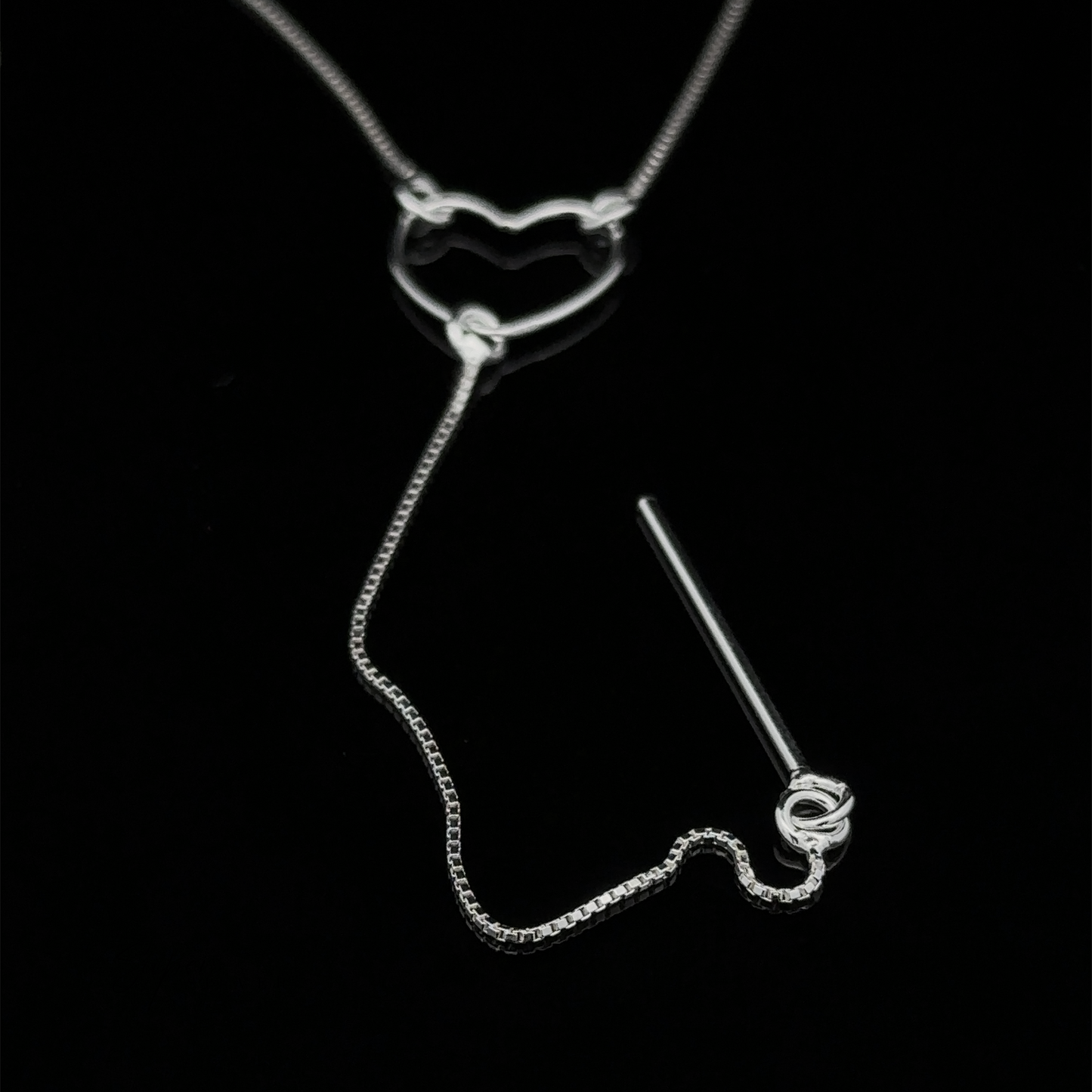 
                  
                    A delicate Open Heart Lariat Necklace featuring a heart-shaped pendant and a thin chain, displayed on a black background.
                  
                