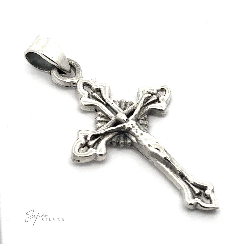 
                  
                    Close-up of a detailed Crucifix Charm with an ornate design and a bail for attaching to a chain. Little text at the bottom reads "Super Silver".
                  
                