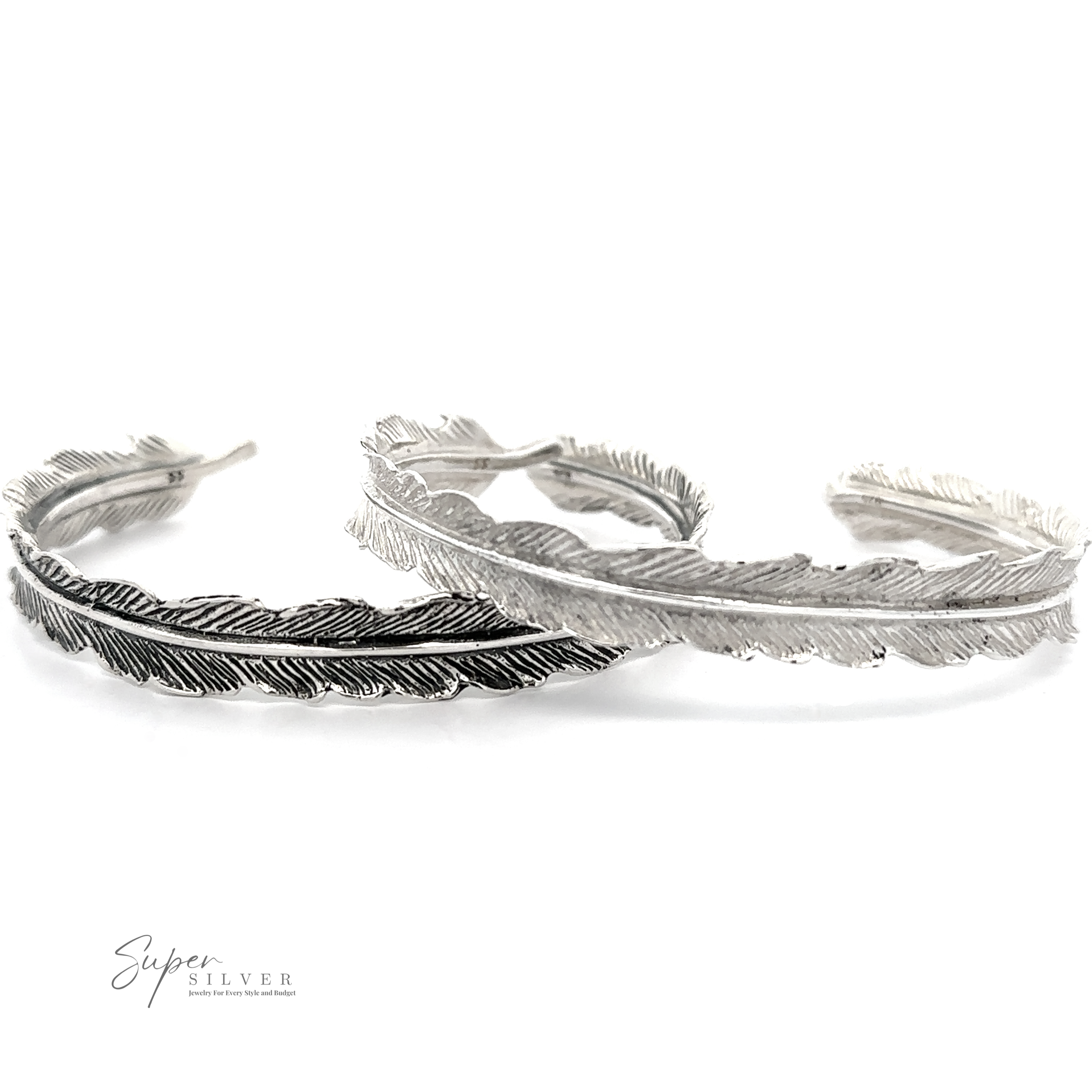 Two .925 sterling silver Detailed Feather Cuff bracelets with intricate detailing, one darker and other lighter in color, positioned side by side on a white background. The oxidized feather cuff design adds a vintage feel. The logo "Super Silver" is visible in the bottom left corner.