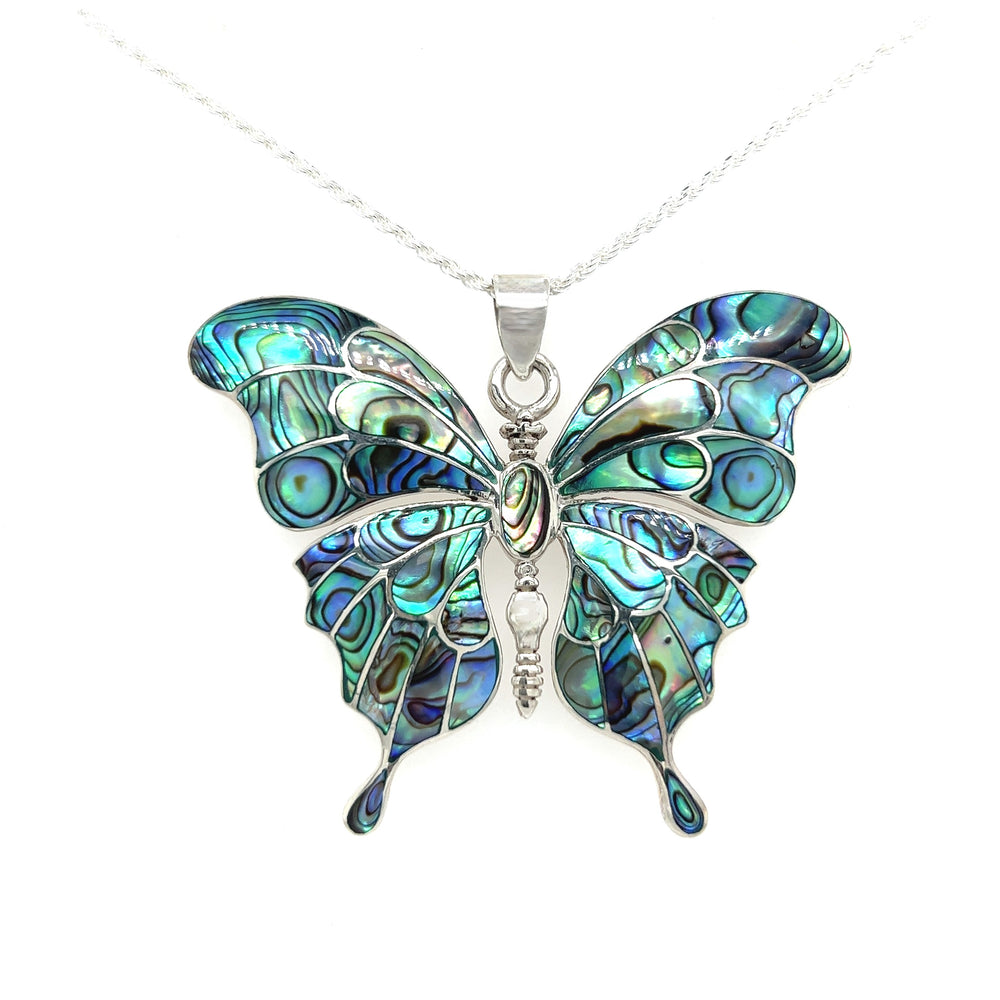 The Stunning Inlay Butterfly Pendant features a sterling silver necklace with butterfly design, adorned in iridescent blue, green patterns, and shimmering turquoise stone.