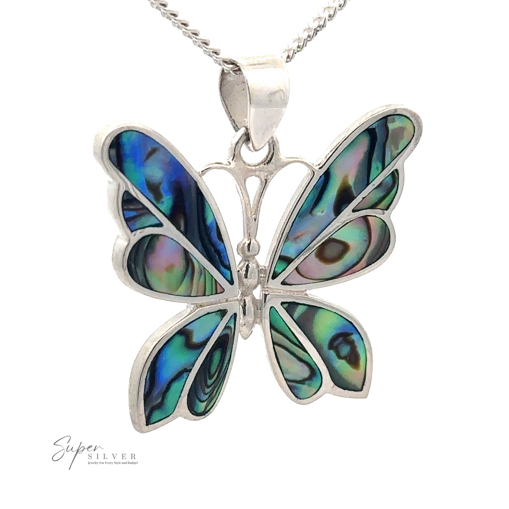 A Medium Inlay Butterfly Pendant with intricate blue, green, and black patterns on its wings hangs from a silver chain. The Super Silver logo is in the bottom left corner.