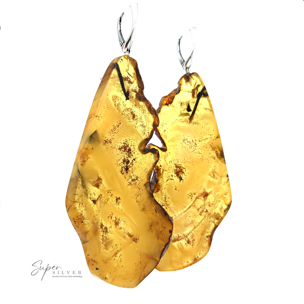 
                  
                    A pair of Designer Raw Cognac Amber Slab Earrings with silver hooks, featuring a rough and textured surface. The logo "Super Silver" is visible in the bottom left corner, highlighting these stunning handcrafted earrings.
                  
                