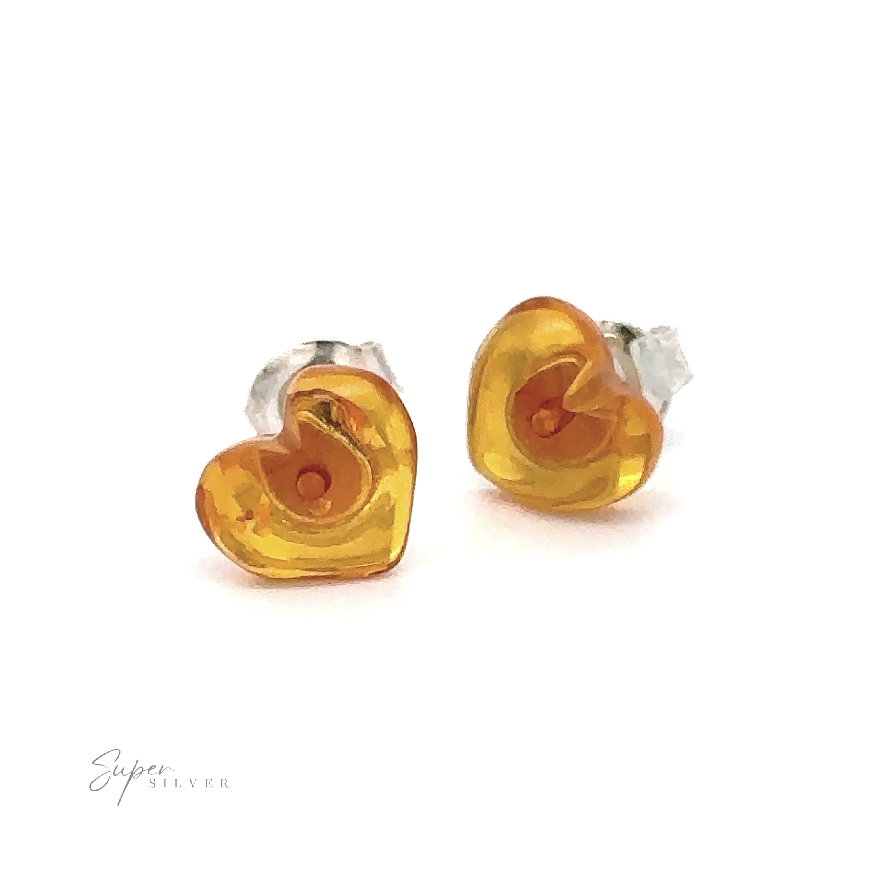 Heart-shaped amber earrings with silver posts, photographed on a white background. "Super Silver" is written in small text in the bottom left corner. These Amber Heart Studs showcase Baltic Amber Jewelry at its finest.