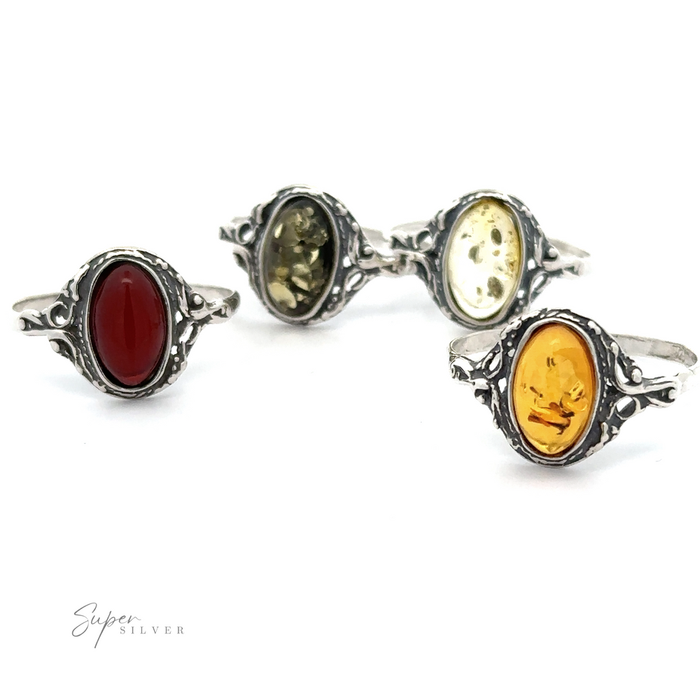 Three delicate Baltic amber rings with antique settings in cognac, greenish, and yellowish hues, displayed against a white background.