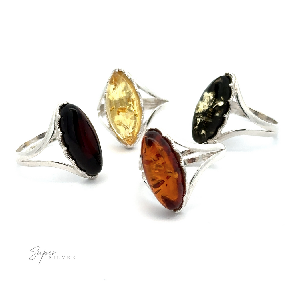 Four silver rings, each featuring an oval-shaped gemstone in various colors: dark red, yellow, orange, and black. One ring highlights a Marquise-Shaped Baltic Amber Adjustable Ring. The rings, complemented by adjustable bands for comfort, are arranged in a semi-circle on a white background.