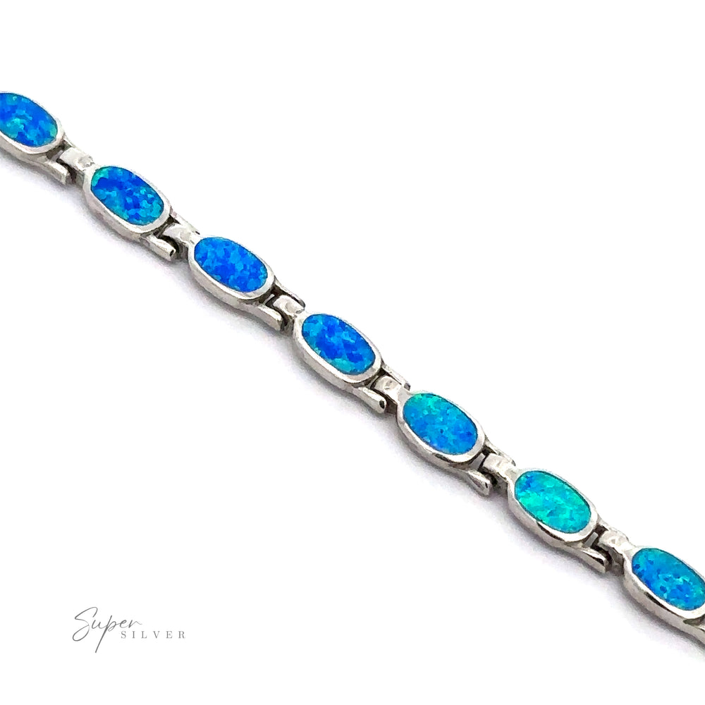 
                  
                    The Oval Lab-Created Opal Bracelet exudes modern elegance with its oval-shaped blue opal stones, each set in individual links of .925 Sterling Silver against a white background.
                  
                