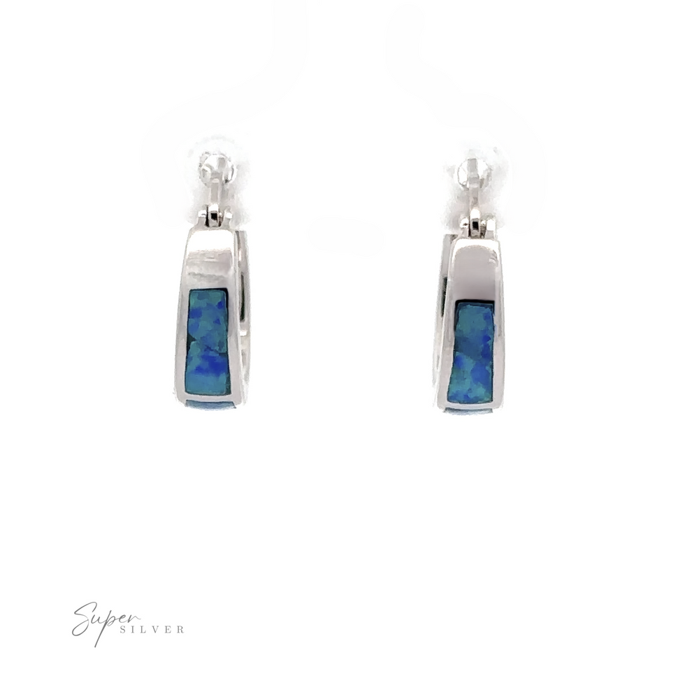 
                  
                    The Blue Lab-Created Opal Huggie Hoop Earrings, featuring rectangular blue and green iridescent stones at the center and enhanced with a rhodium finish, are displayed against a white background.
                  
                