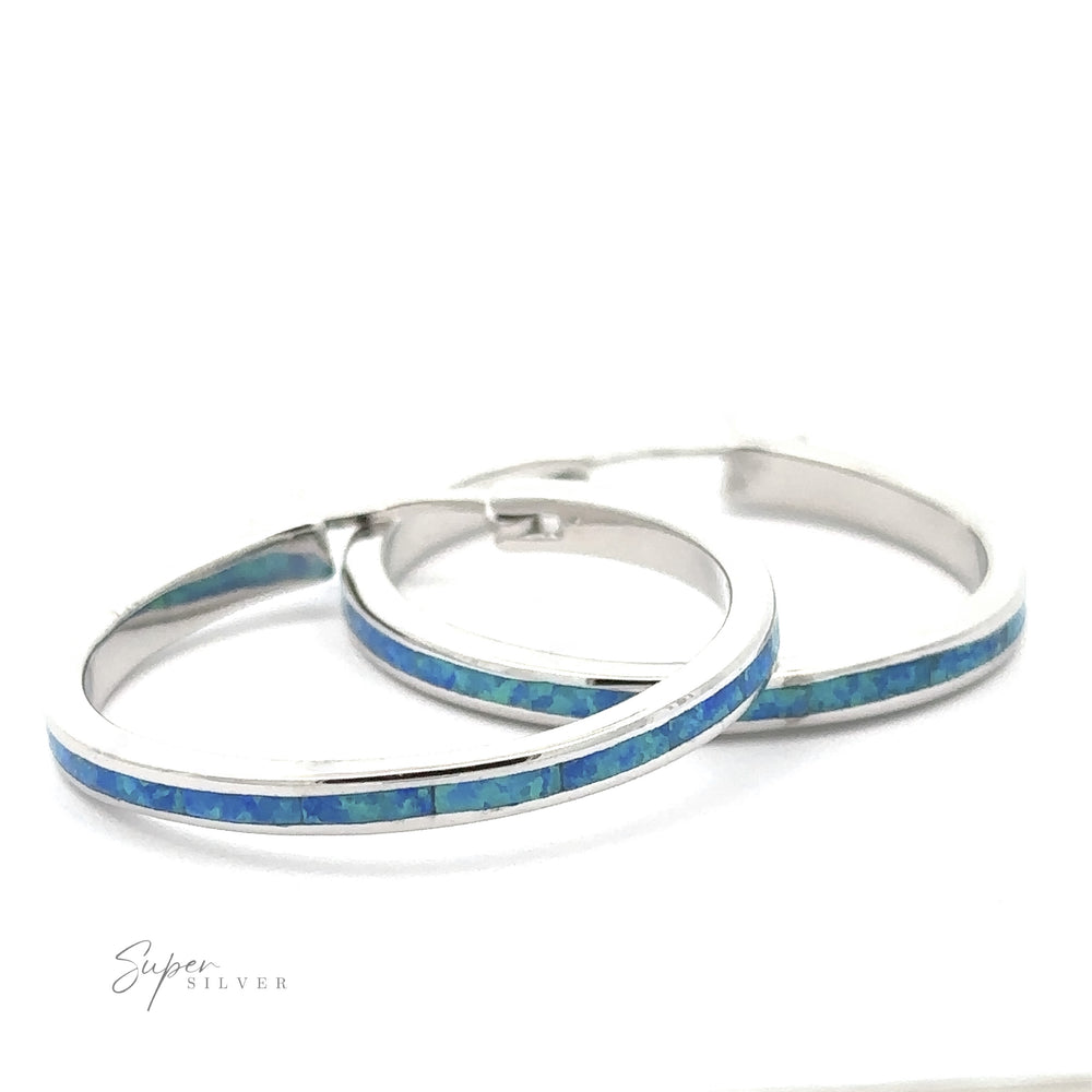 
                  
                    A pair of 30mm Blue Opal Hoop Earrings are placed on a white background. The words "Super Silver" are visible in the lower-left corner of the image.
                  
                