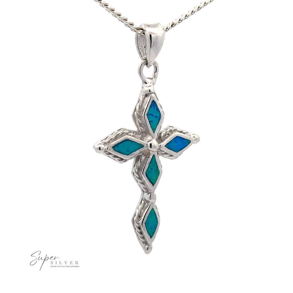
                  
                    A Blue Opal Cross Pendant featuring blue opal inlays and diamond-cut stones, hanging from a silver chain with a rhodium finish. The logo "Super Silver" is visible in the lower left corner.
                  
                
