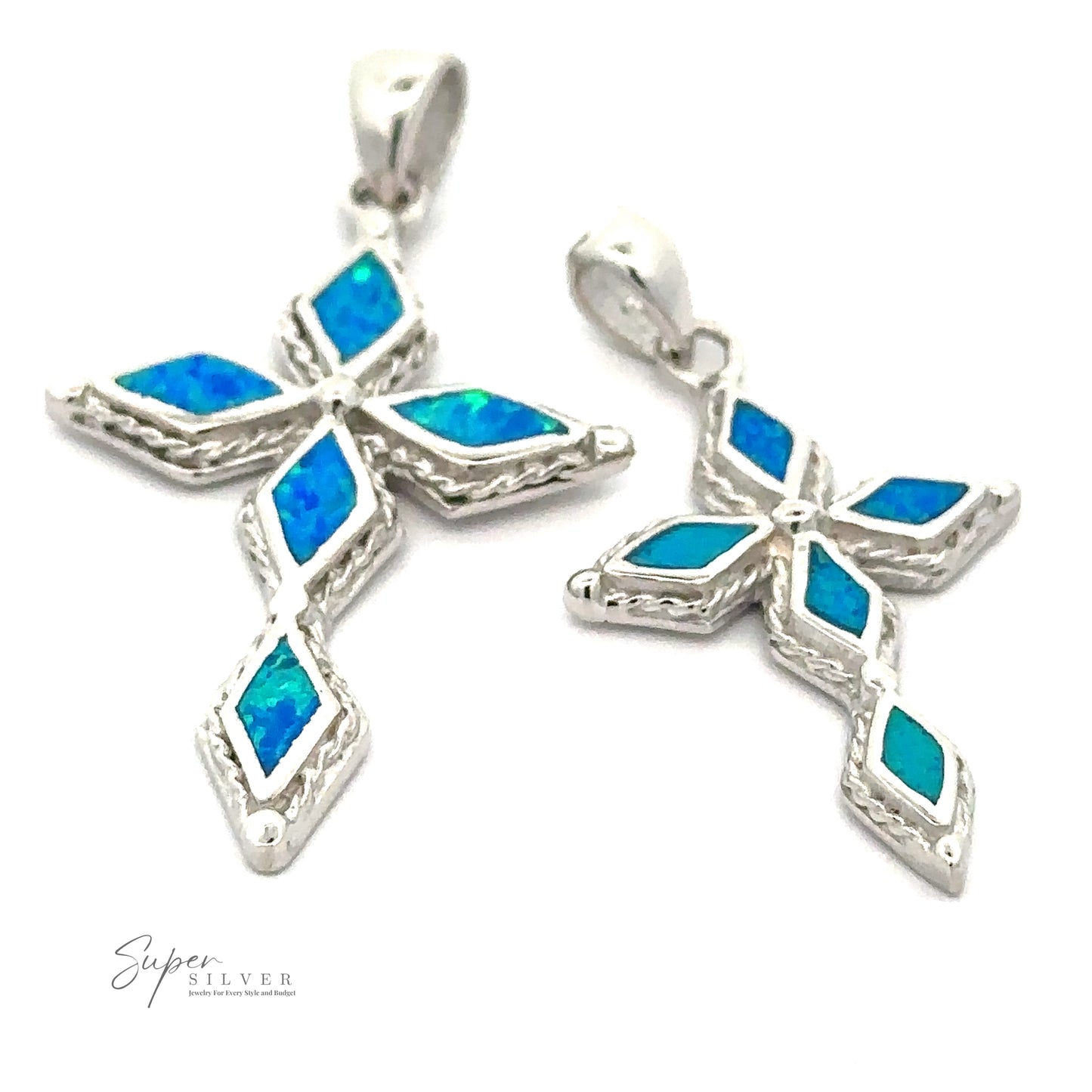 A close-up image of two Blue Opal Cross Pendants with diamond-cut stones and blue opal inlays on a white background. The pendants, featuring a gleaming rhodium finish, have decorative edge details and different loop designs at the top.