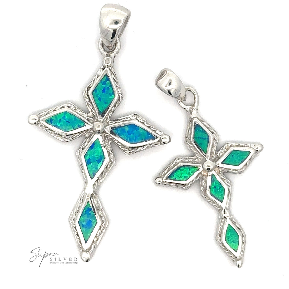 
                  
                    Two Blue Opal Cross Pendants shaped like stylized crosses, featuring inlaid blue and green gemstones in a geometric pattern with a striking rhodium finish.
                  
                