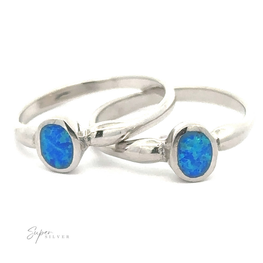 A pair of elegant silver rings with Petite Blue Lab Opal gemstones on a white background.