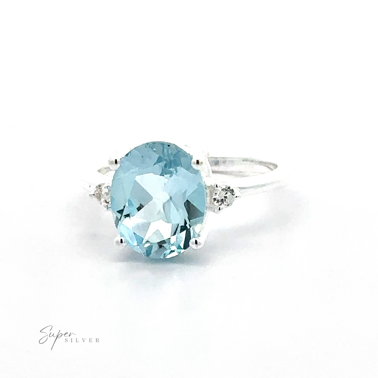
                  
                    A Brilliant Pronged Oval Gemstone Ring featuring a large oval aquamarine stone in a prong setting, flanked by small diamonds, displayed on a plain white background.
                  
                