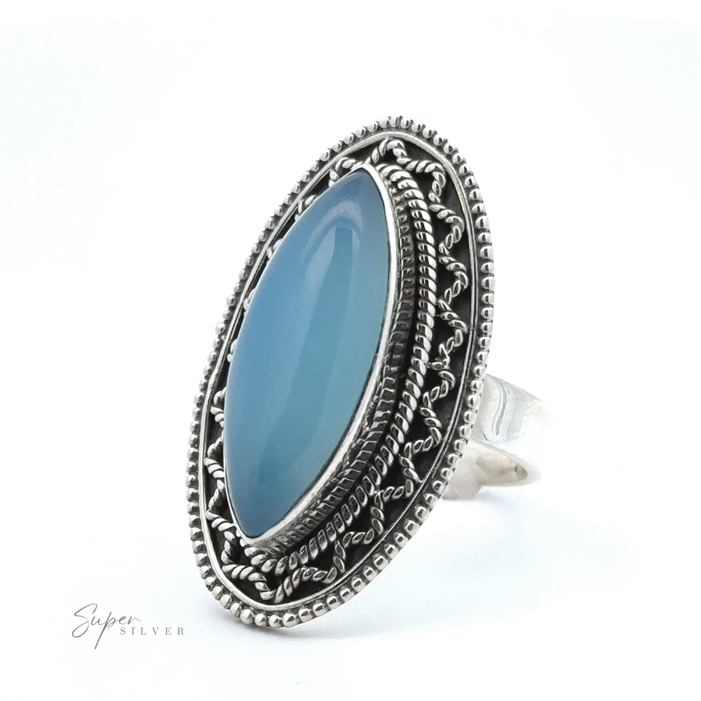 
                  
                    A stunning Marquise Shaped Gemstone Ring With Vintage Shield Border with intricate designs featuring a large marquise-shaped, oval blue gemstone set in the center. The ring is displayed against a white background, adding a Bohemian twist to its timeless elegance.
                  
                