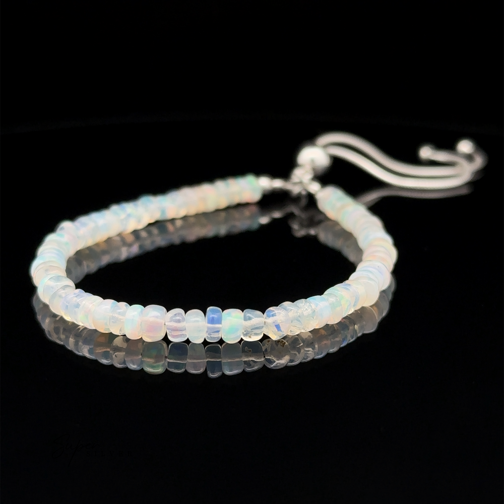 An Ethiopian Opal Beaded Bracelet made of small translucent beads with an adjustable length closure, displayed on a black reflective surface.