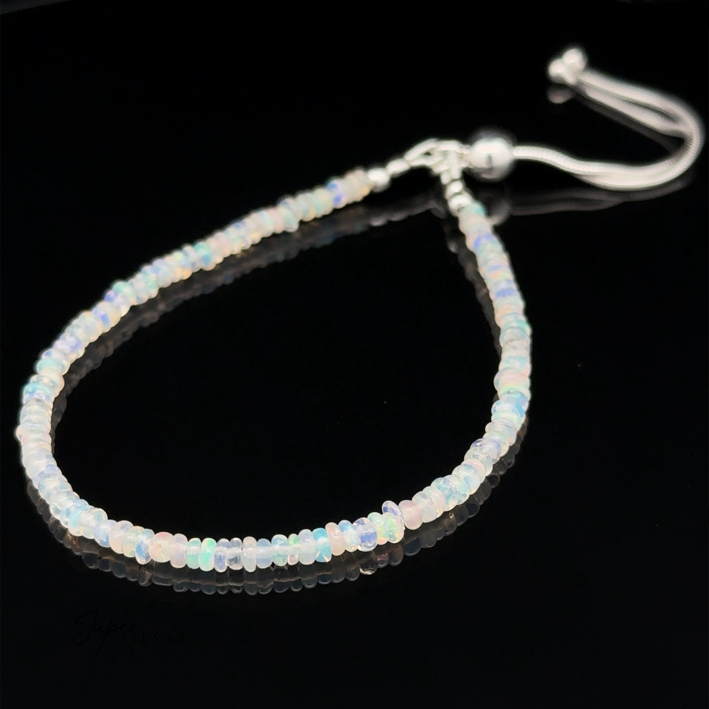 
                  
                    A delicate Ethiopian Opal Beaded Bracelet with an adjustable length closure is displayed on a black surface. The beaded bracelet features small, translucent beads in a variety of soft, iridescent colors.
                  
                