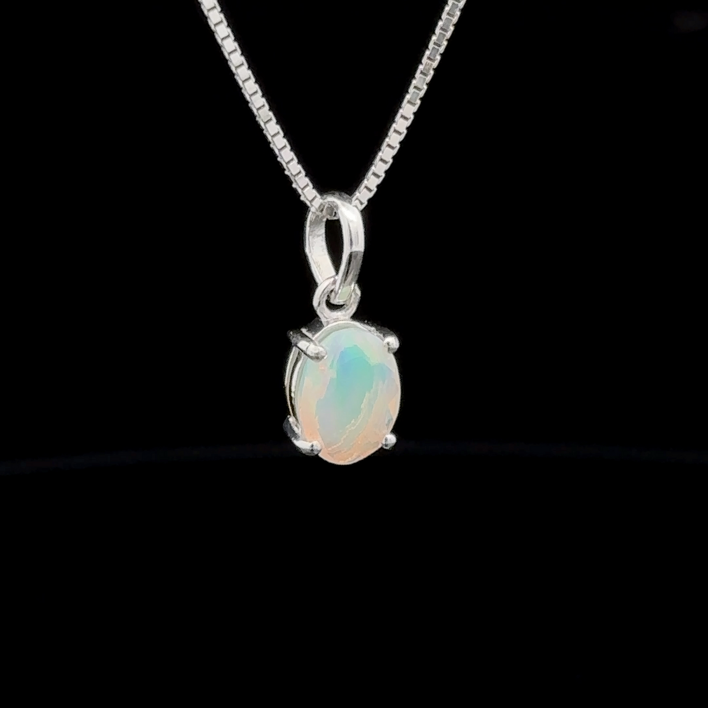 
                  
                    A sterling silver necklace showcasing a Tiny Oval Pronged Ethiopian Opal Pendant, elegantly set against a black background.
                  
                