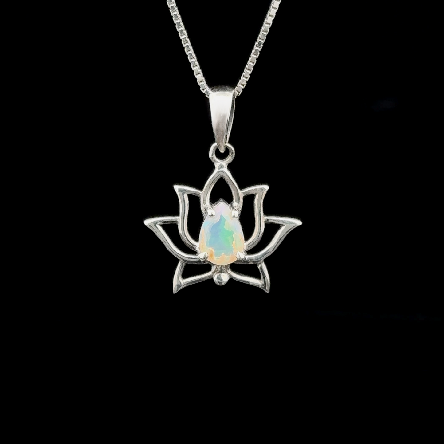 
                  
                    The Ethiopian Opal Lotus Pendant, featuring a sterling silver lotus flower and a central opal gemstone, hangs elegantly from a chain against a black background.
                  
                