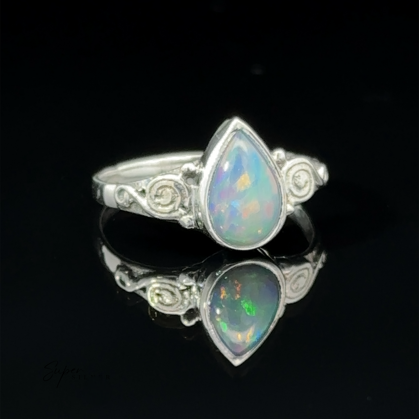 
                  
                    Silver teardrop gemstone ring with colorful speckles, displayed on a reflective black surface.
                  
                