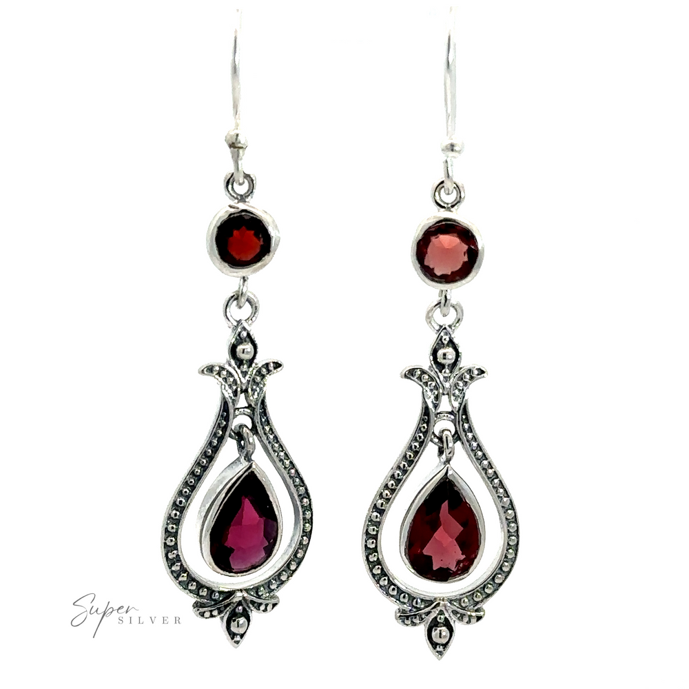 
                  
                    A pair of ornate, .925 Sterling Silver Vintage-Styled Teardrop Earrings with Gemstones featuring red garnet gemstones, with teardrop-shaped and round stones, displayed on a white background. These vintage-style teardrop earrings exude a Bali style charm.
                  
                