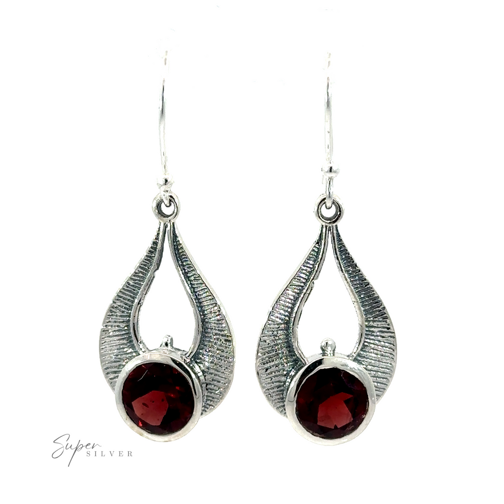 A pair of Winged Gemstone Earrings in silver, showcasing a garnet gemstone at the center, adorned with a textured, curving design around the stone. The "Super Silver" logo is prominently displayed in the bottom left corner.