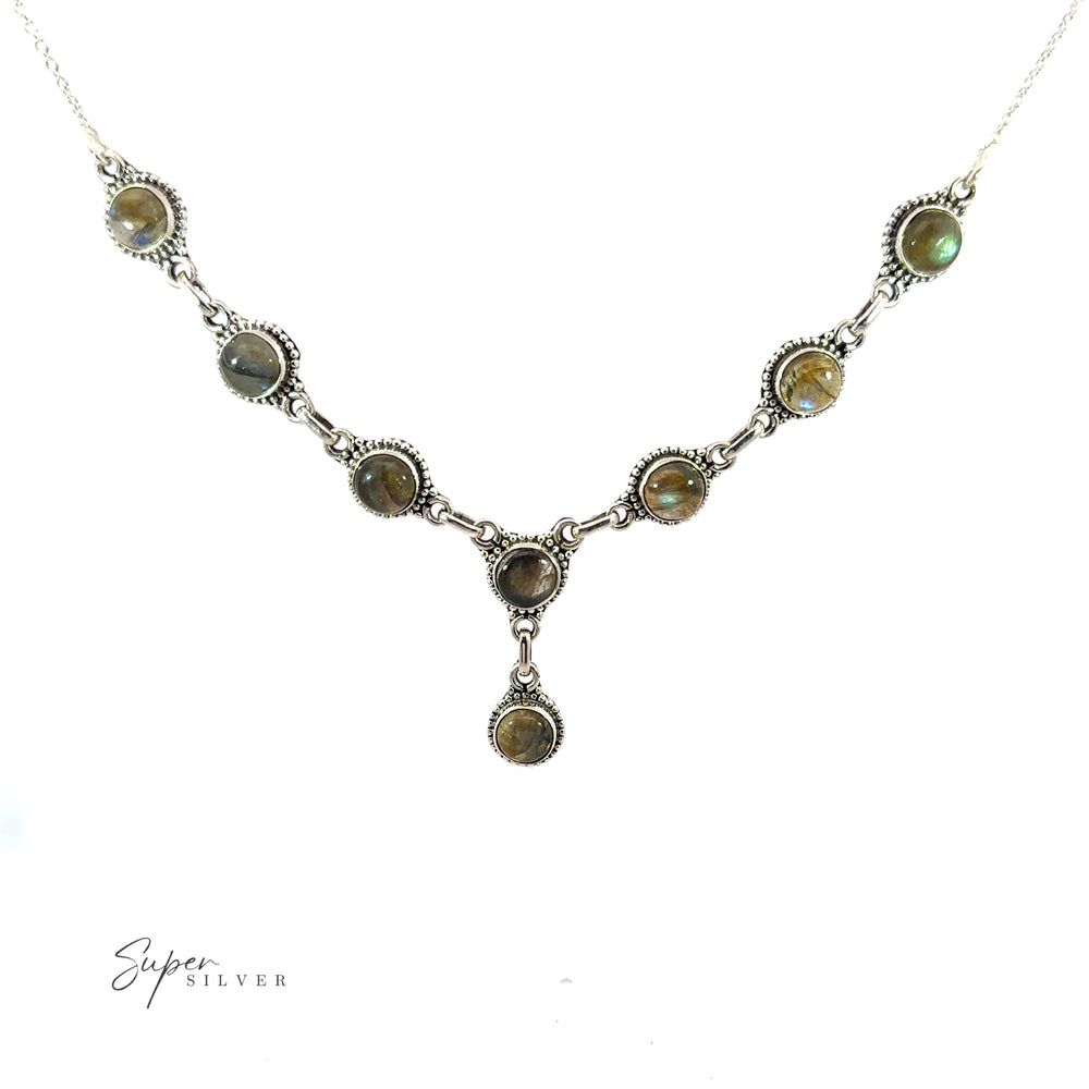 
                  
                    A Round Gemstone Y Necklace with Ball Border featuring a series of round, green gemstones linked together, with one gemstone hanging at the center. This bohemian style jewelry piece lies elegantly on a white background.
                  
                