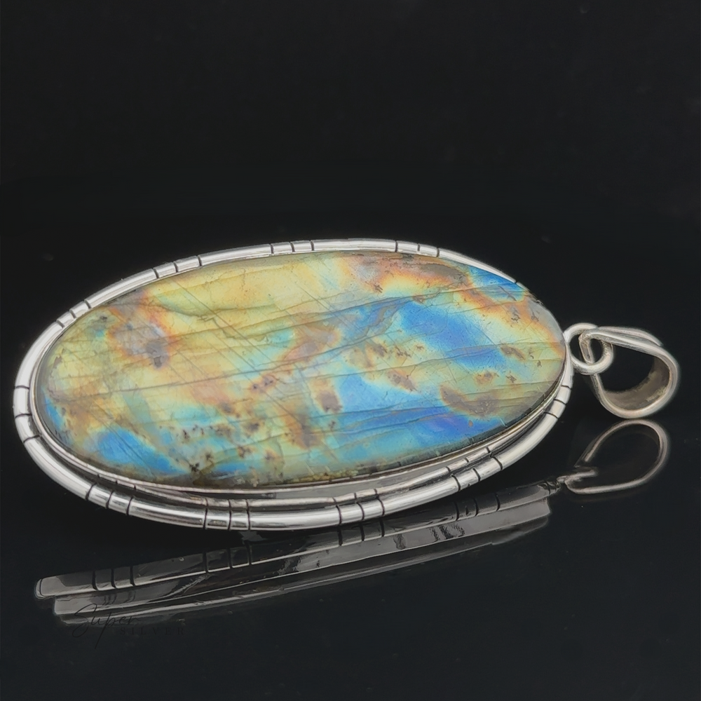 
                  
                    An XL Statement Oval Labradorite Pendant set in a sterling silver jewelry frame, displayed against a black background.
                  
                