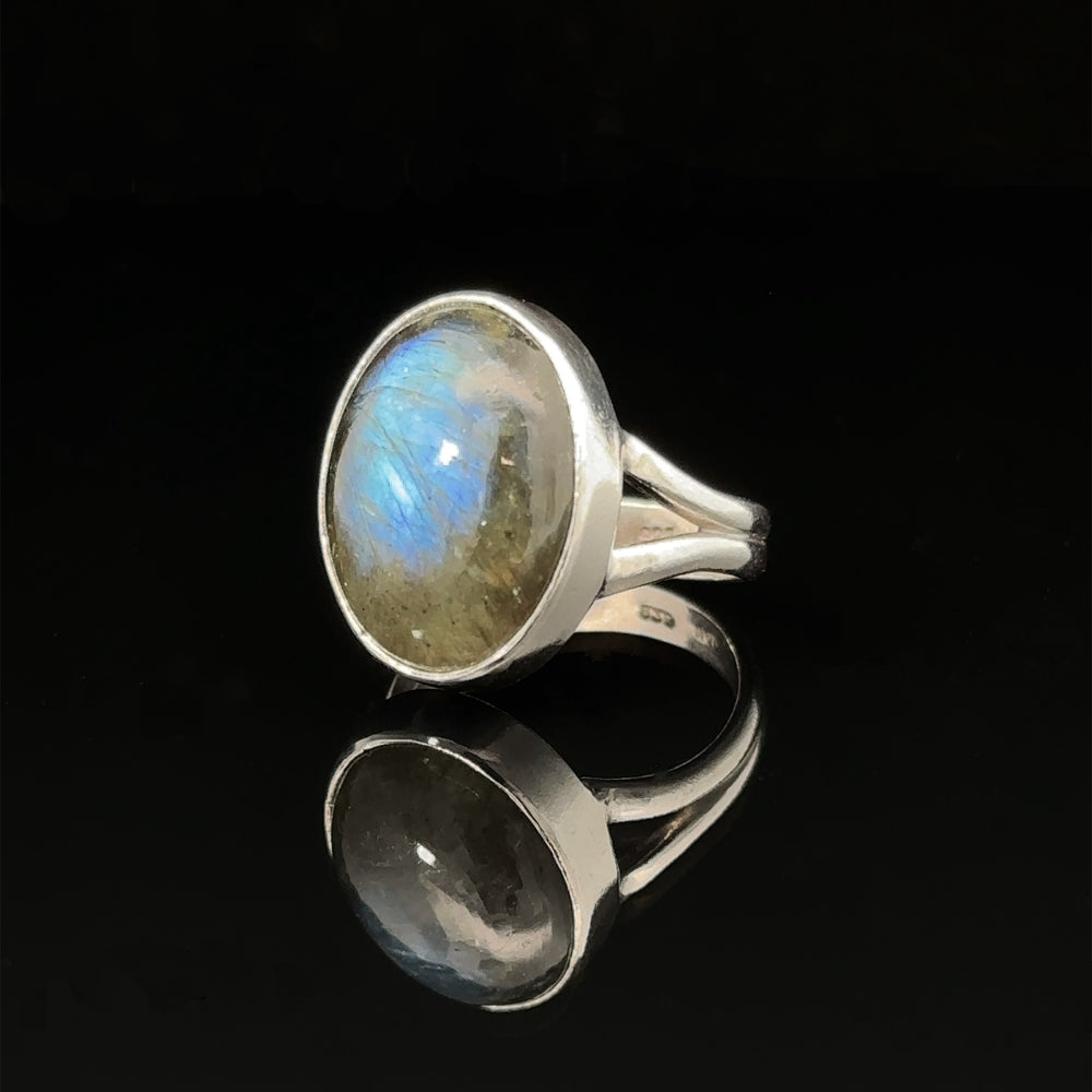 Heavy Oval Labradorite Ring with an oval moonstone set on a reflective surface.