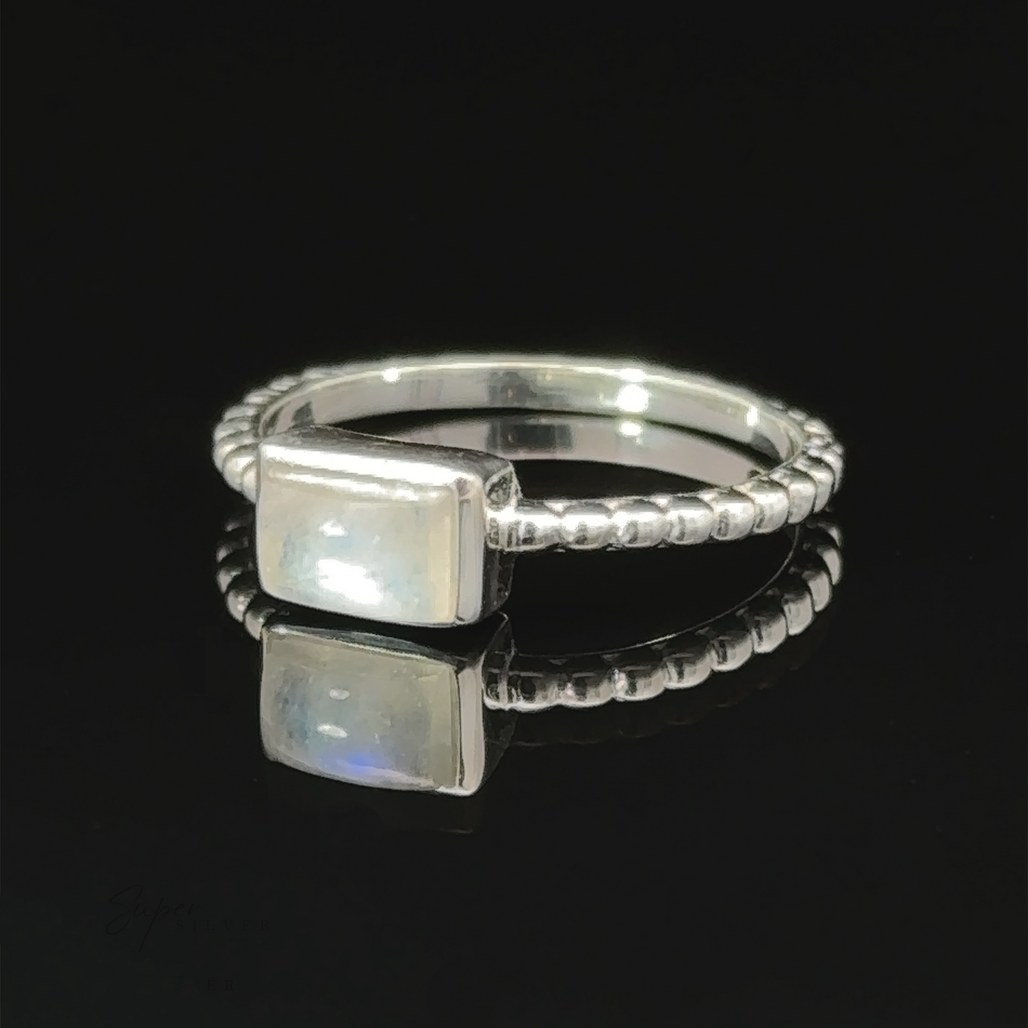 
                  
                    Rectangular Gemstone Ring with Beaded Band displayed on a reflective surface.
                  
                