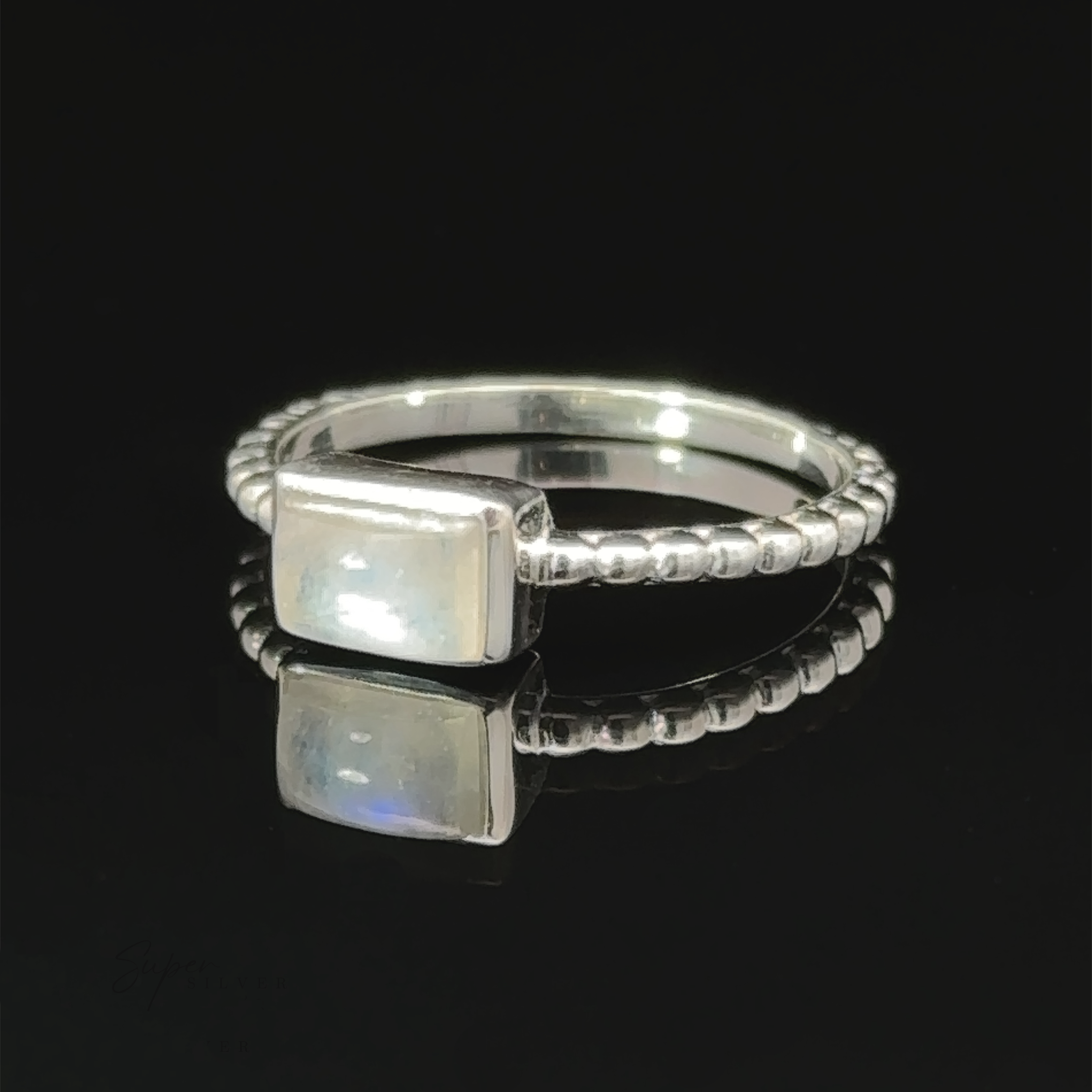 Rectangular Gemstone Ring with Beaded Band displayed on a reflective surface.