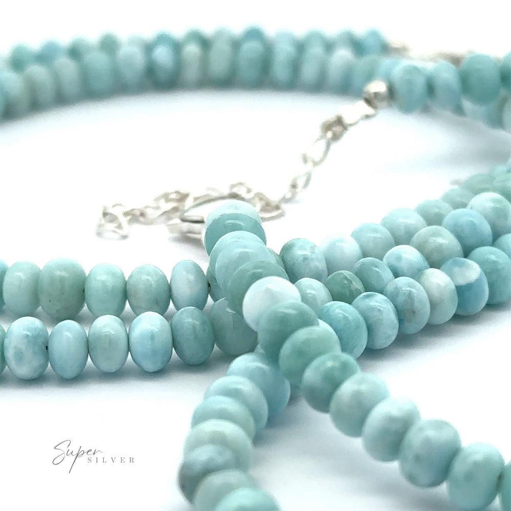 Close-up of light blue and turquoise Larimar Beaded Necklace with silver clasp, showcasing its smooth, rounded shapes and varied hues, reminiscent of a Caribbean necklace.