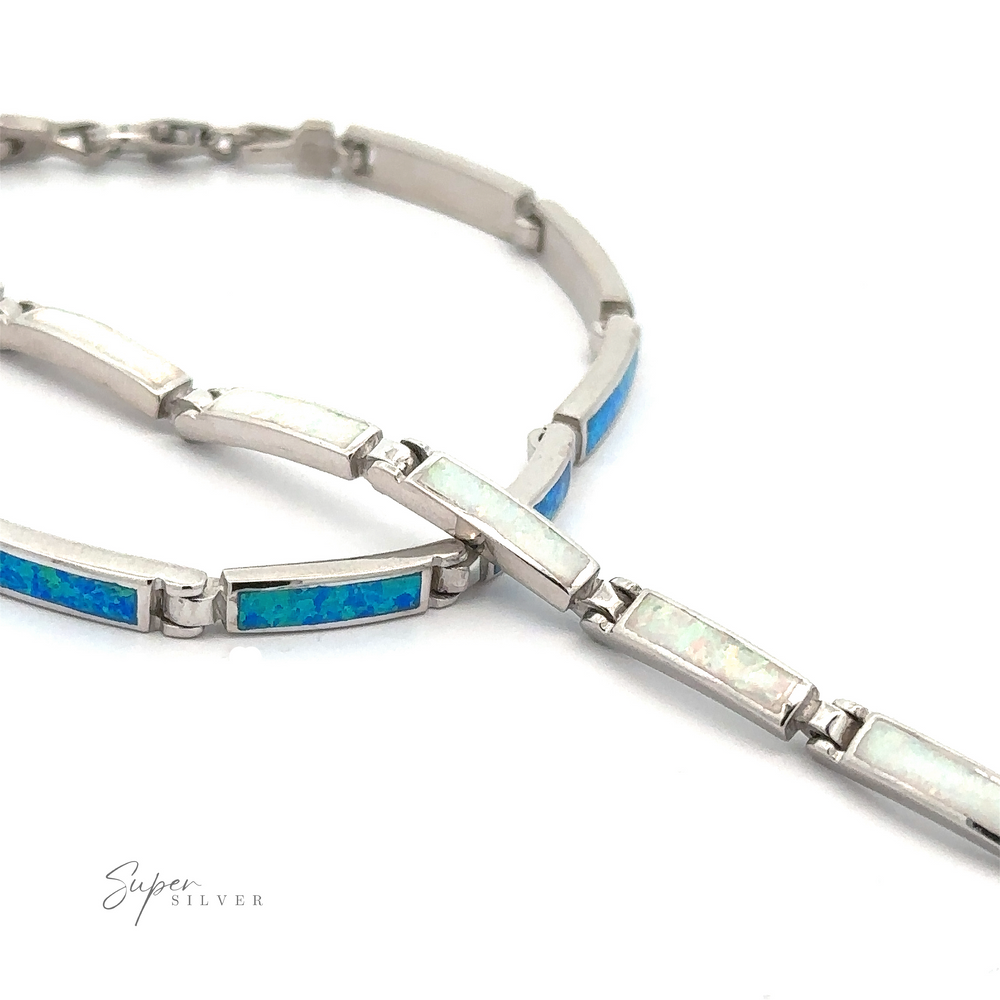 The Long Rectangle Lab-Created Opal Bracelet features alternating blue and white opal inlays, elegantly arranged in a looped design with the clasp gently visible at one end. This piece beautifully embodies the sophistication of Opal Glow Jewelry.