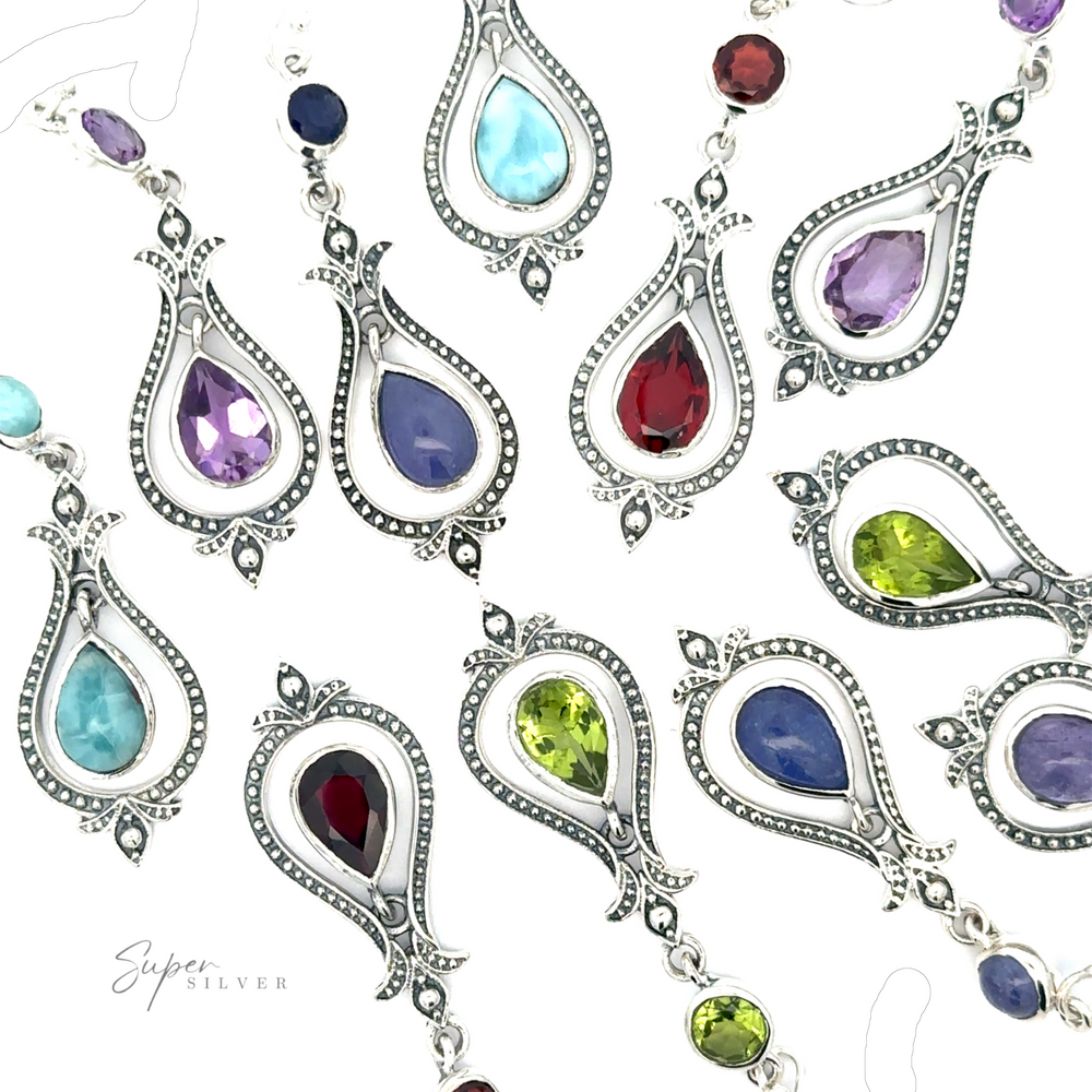 A collection of silver pendants with pear-shaped gemstones in various colors, including red, blue, purple, and green, displayed on a white background. Also available are Vintage-Styled Teardrop Earrings with Gemstones to complement your jewelry ensemble perfectly.