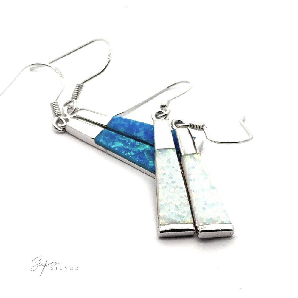 A pair of Elegant Long Opal Earrings with angular silver settings, featuring triangular blue and white iridescent lab-created opal stones. Perfect for the contemporary artsy woman, the brand name 