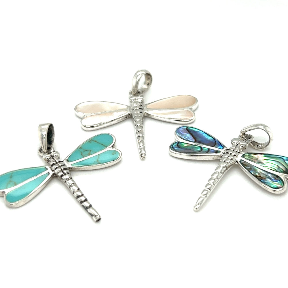 Three Super Silver Dragonfly Inlay Stone Pendants with abalone and mother of pearl accents on a white background.