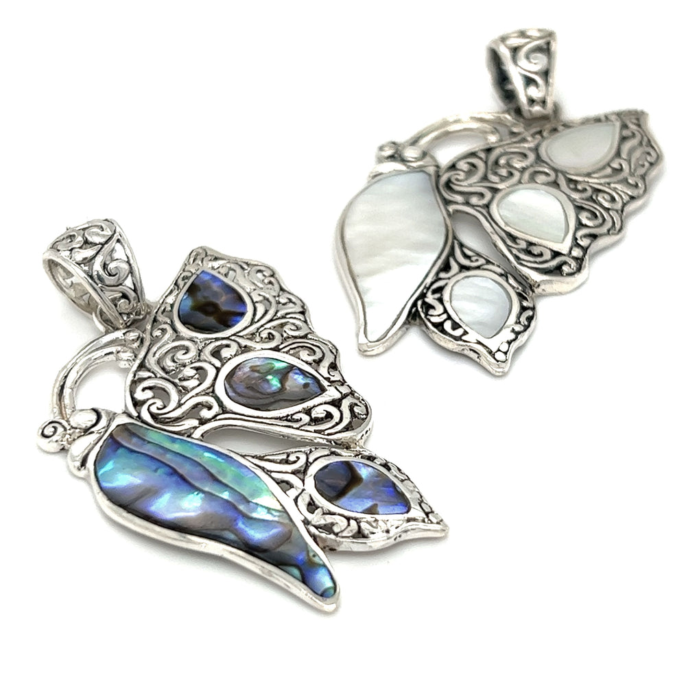 A pair of Filigree Butterfly Inlay Pendants with blue and white shells, symbolizing transformation.