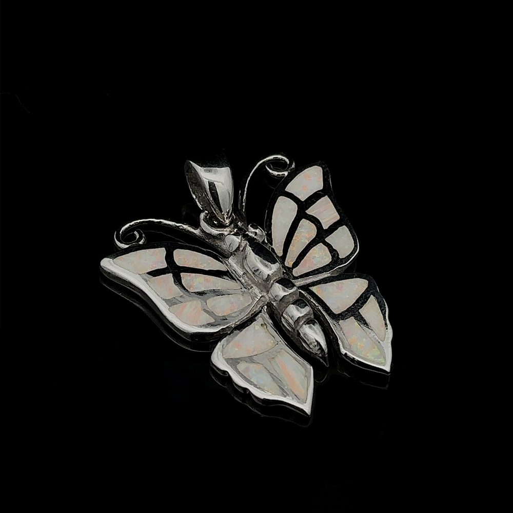 
                  
                    Lab-Created Opal Butterfly Pendant featuring a sterling silver butterfly adorned with lab-created opal inlays against a black background.
                  
                