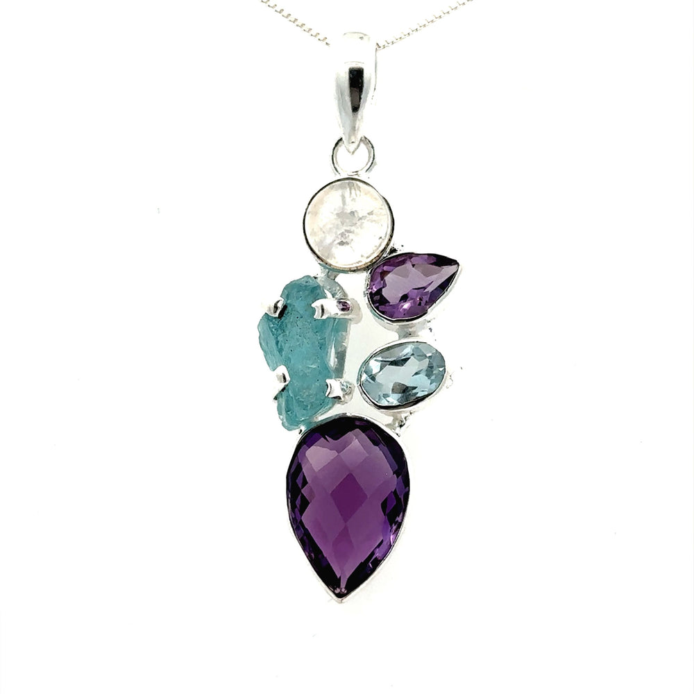 The Amethyst Multi Stone Pendant, featuring five gemstones in an array of shapes and colors—purple amethyst, teal, clear, and blue—is elegantly set in a silver mount that exemplifies bohemian jewelry as it hangs gracefully on a chain.