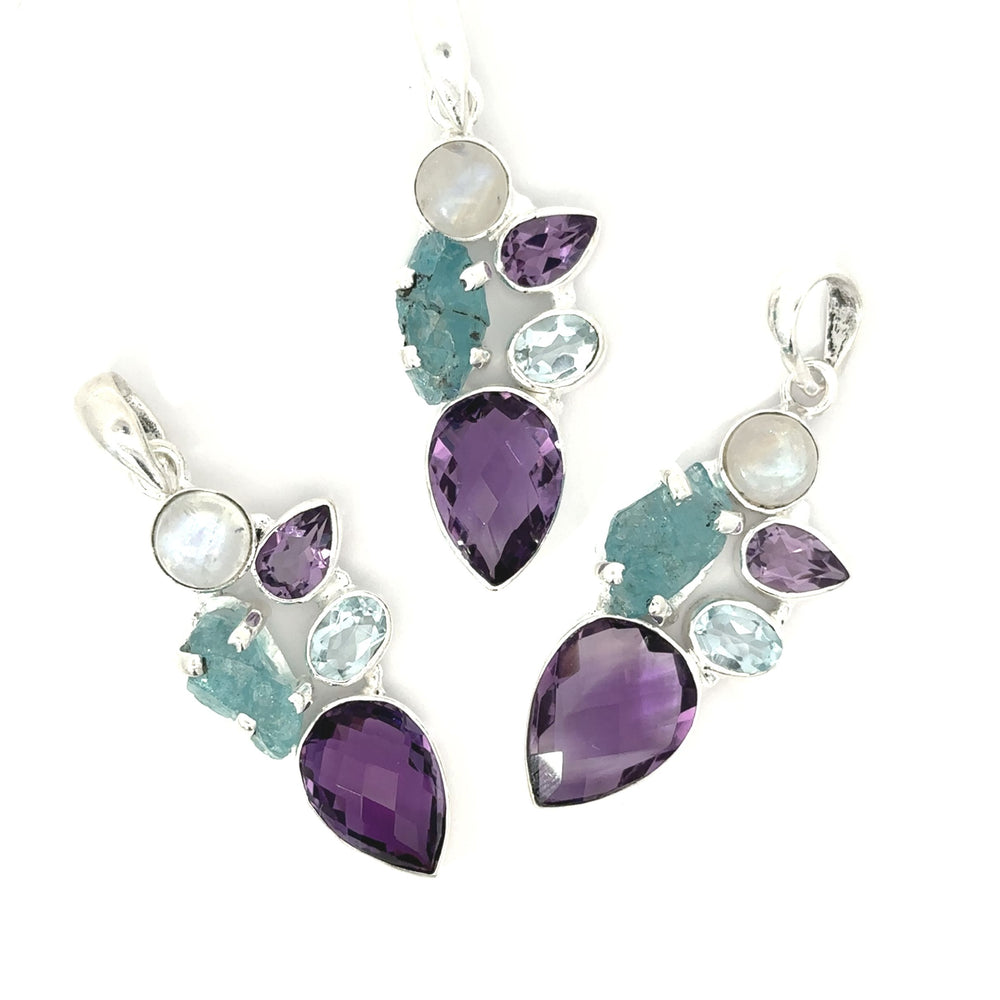 
                  
                    The Amethyst Multi Stone Pendant presents three silver pendants with an abstract design on a white background, embracing a bohemian jewelry style. It features a vibrant mix of purple, teal, and clear gemstones in teardrop and oval shapes, echoing the essence of an amethyst pendant.
                  
                