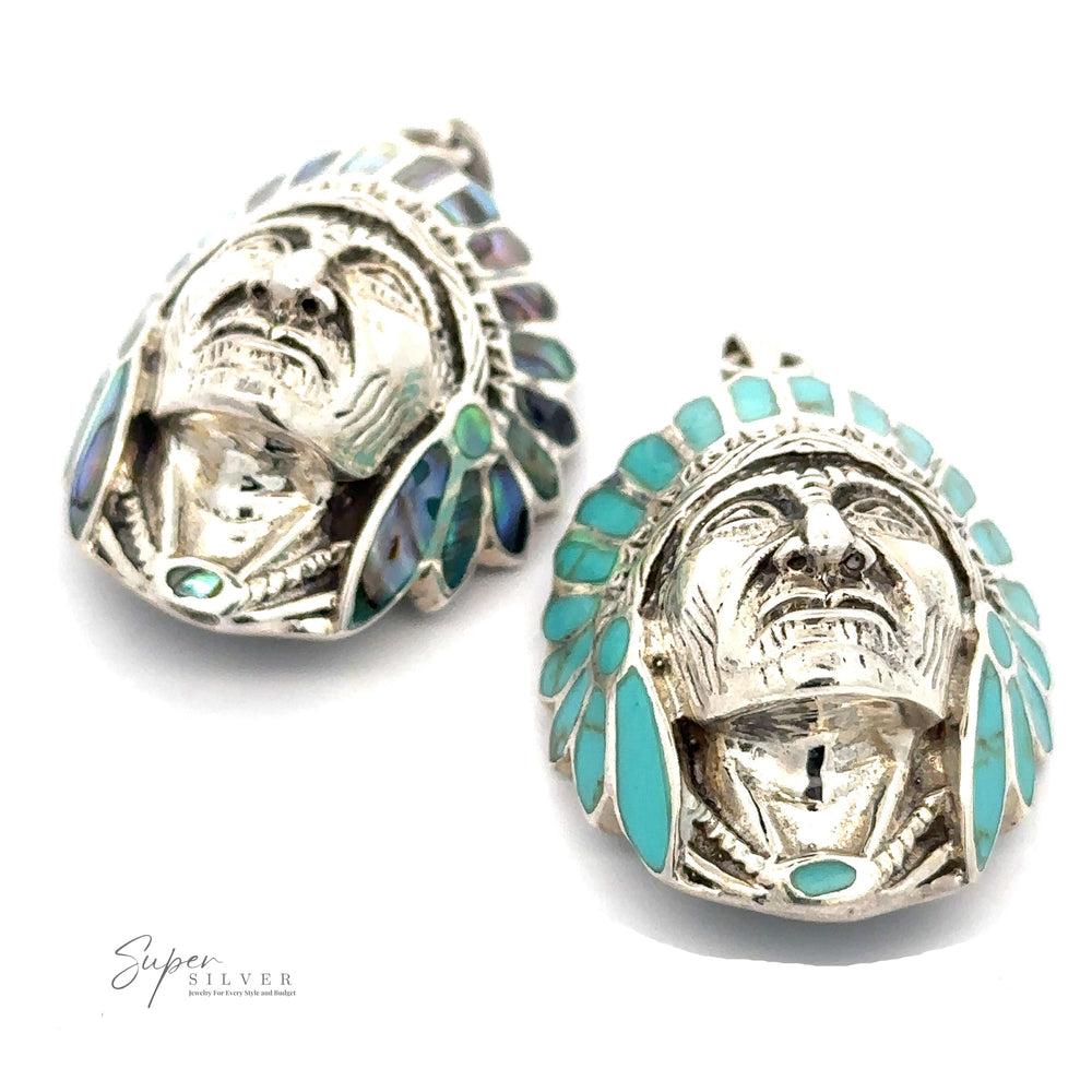 
                  
                    Two Chief Pendant With Inlaid Stones shaped like a Native American chief's head, adorned with turquoise and abalone inlaid headdresses. The text "Super Silver" is visible in the corner.
                  
                