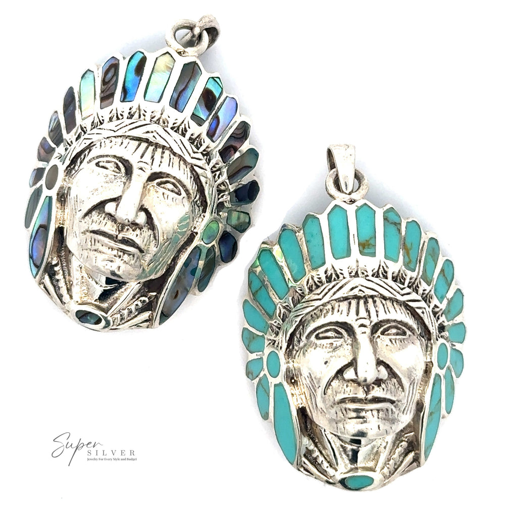 Two sterling silver pendants shaped like faces adorned with headpieces. One pendant has turquoise inlays, while the other has iridescent blue and green inlays. Both feature intricate metalwork reminiscent of a Chief Pendant With Inlaid Stones' traditional artistry.