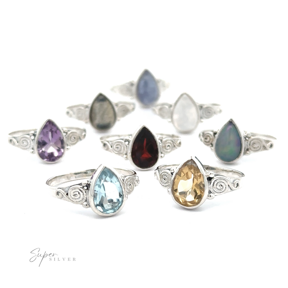 A collection of Teardrop Gemstone Rings With Swirls featuring various teardrop-shaped gemstones including opal, sapphire, and garnet, set on bands with bohemian flair.