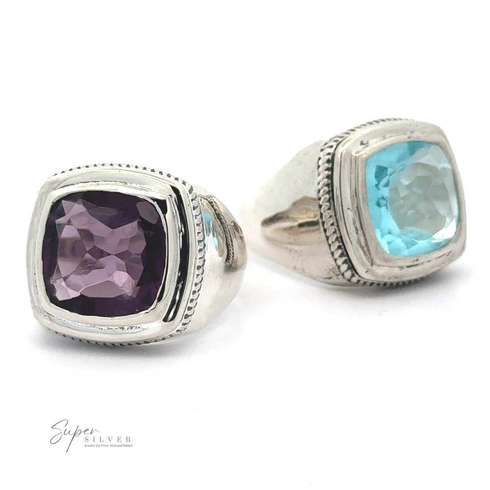 Two Faceted Stone Signet Rings with square-cut gemstones, one amethyst and one blue topaz, are displayed on a white surface. The logo 
