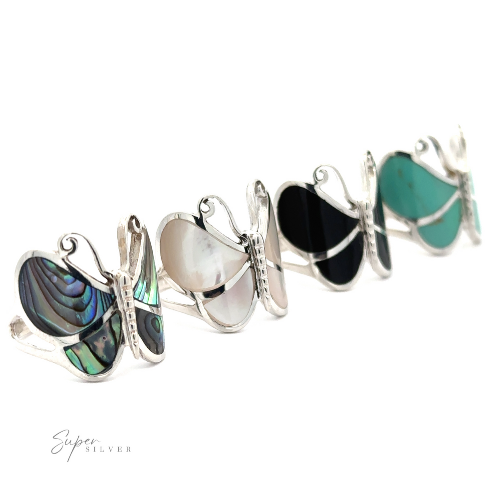 A row of Bold Butterfly Rings with Inlaid Stones, each featuring unique colorful gemstones, displayed against a white background with "super silver" text at the bottom.