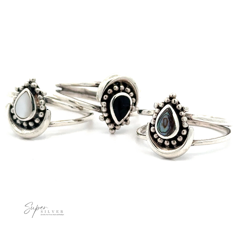 Three Teardrop Rings With Inlaid Stone and Crescent Moon in white, black, and iridescent abalone, displayed upright. This exquisite silverwork jewelry features the Super Silver logo in the lower left corner.