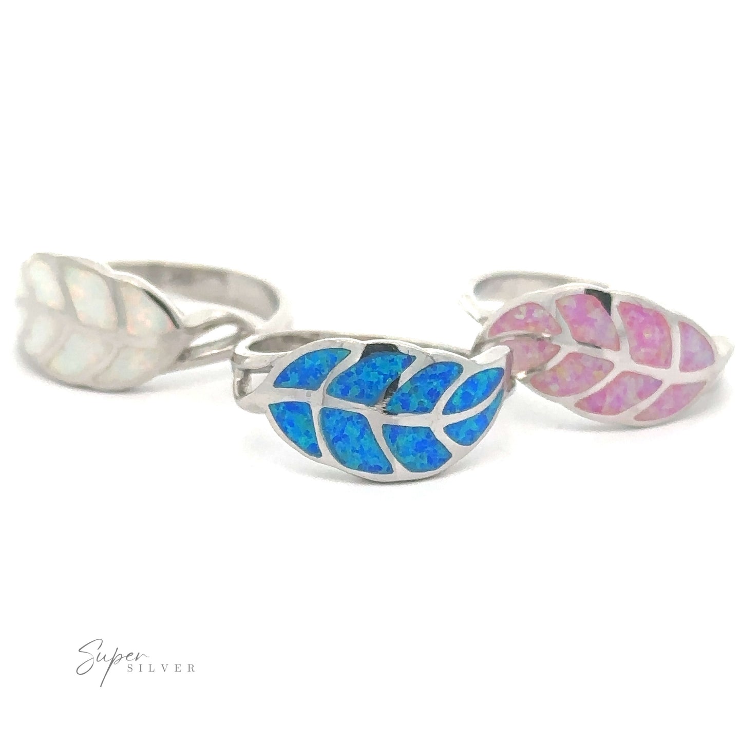A trio of silver rings with leaf-shaped designs inlaid with blue and pink lab opal materials, exuding an ethereal charm.