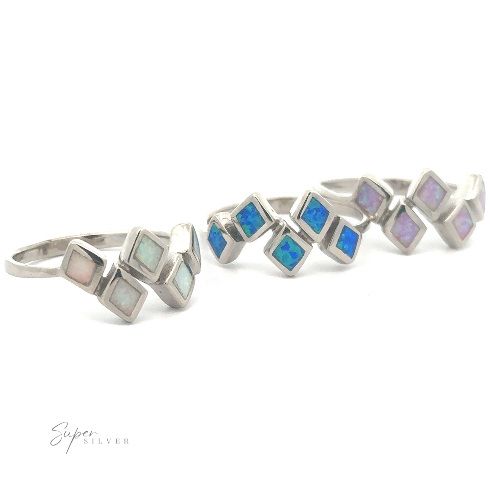 Two diamond pattern lab-created opal rings adorned with square-cut opal stones in varying shades of blue and purple, displayed against a white background.